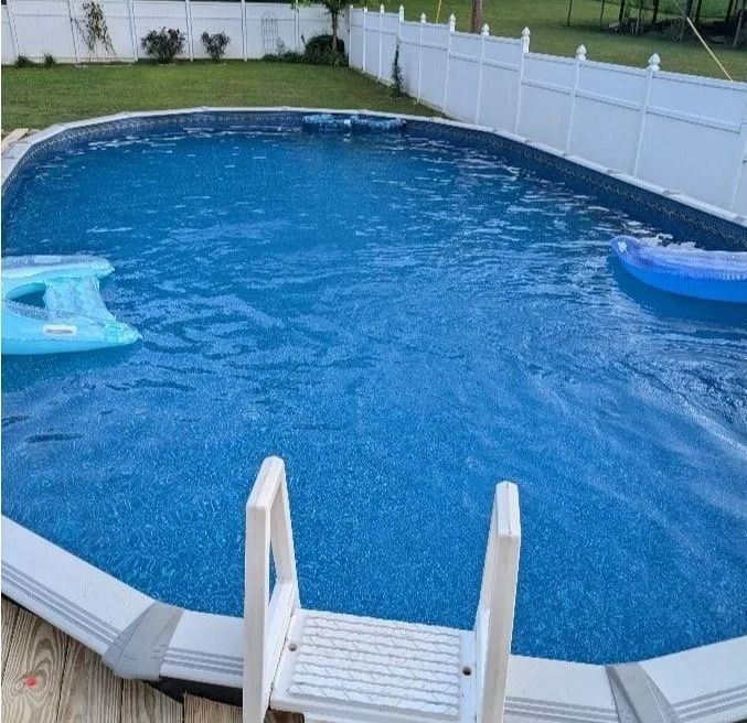 Backyard above-ground pool with two floaties and a white fence around it