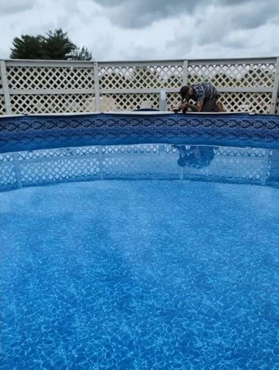 Person sitting by a blue above-ground pool under a cloudy sky