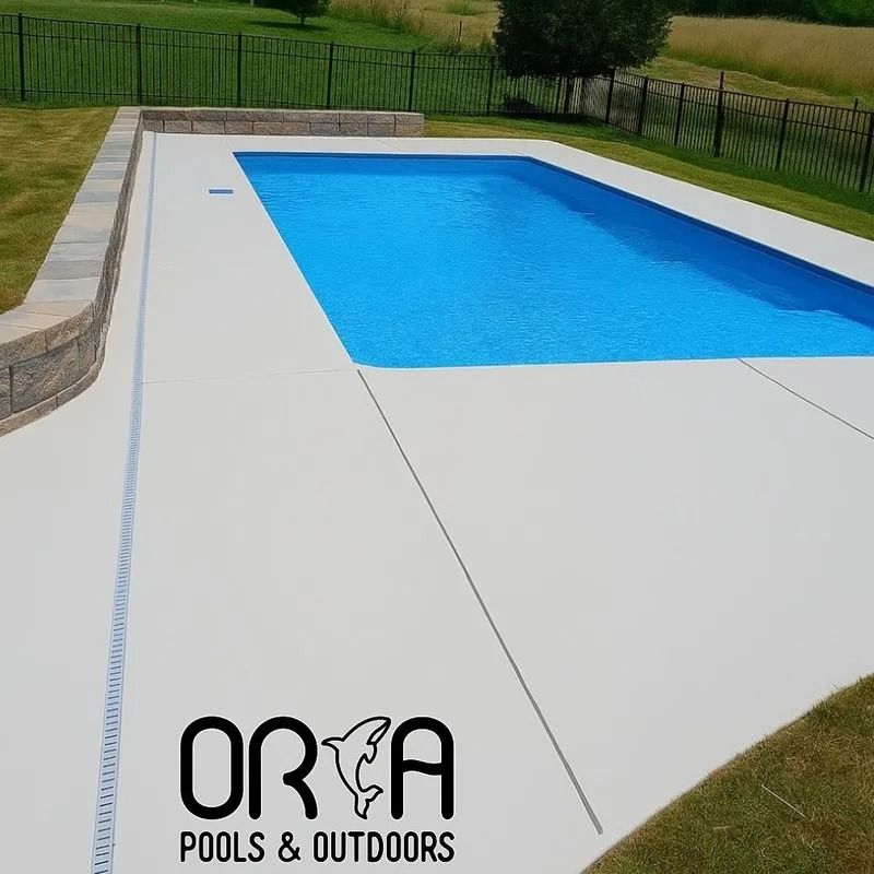 Rectangular outdoor pool with blue water, surrounded by a light concrete deck and grassy yard.