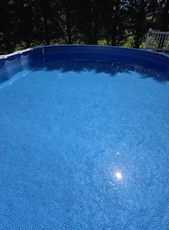 Blue swimming pool with rippling water in a wooded outdoor setting