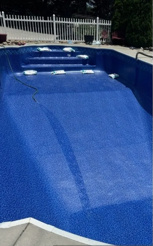 Empty blue swimming pool with a white fence in the background