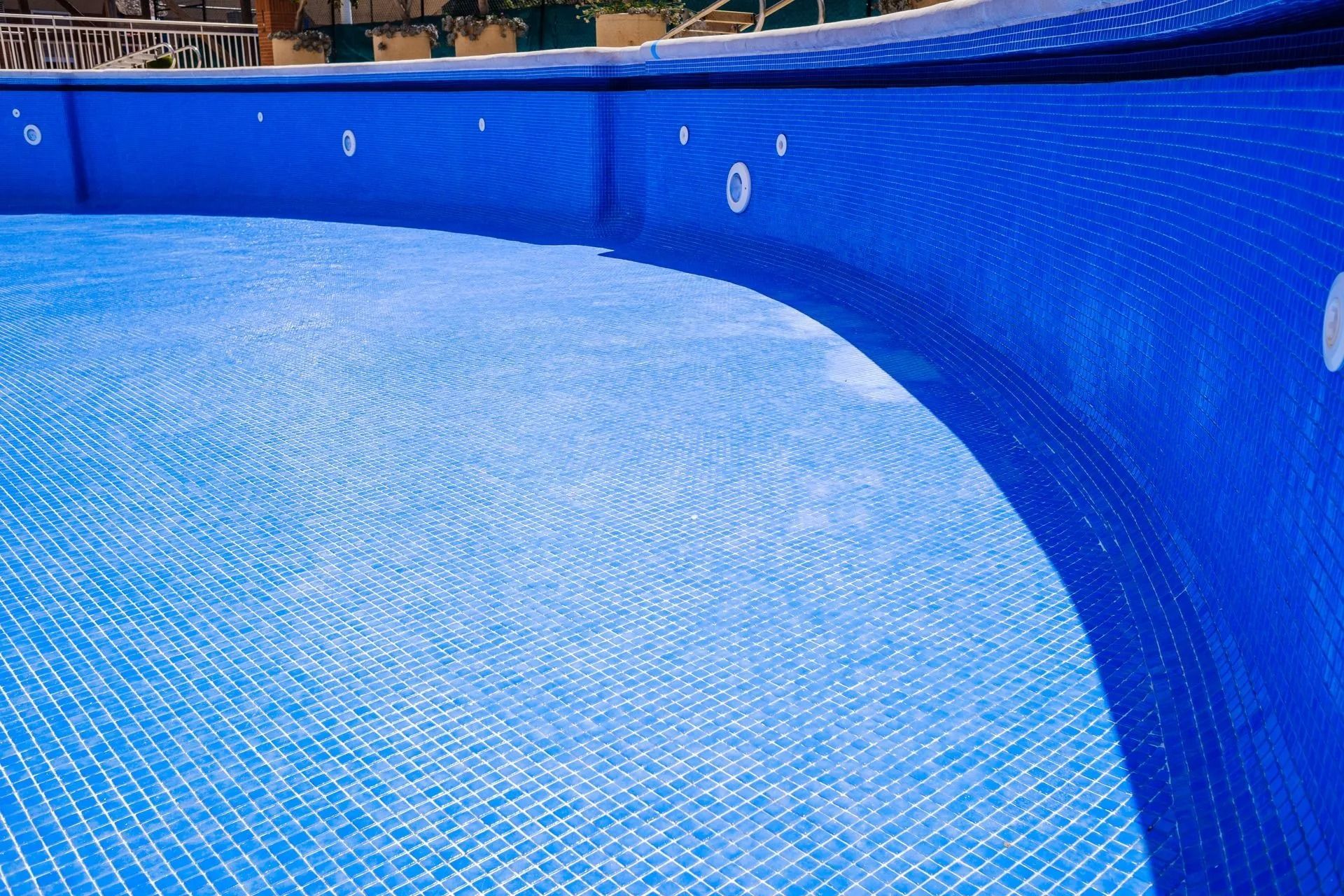 Empty blue swimming pool with curved liner and tiled floor