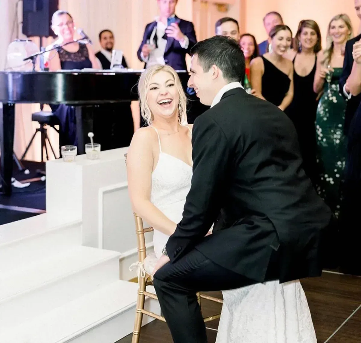 Bride laughing with groom during a seated dance at a wedding reception