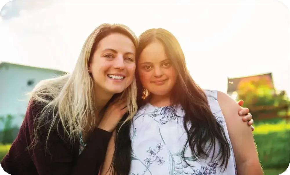 Two Women Are Standing Next To Each Other In Front Of A Table — Unique Life Services In Nelson Bay, NSW