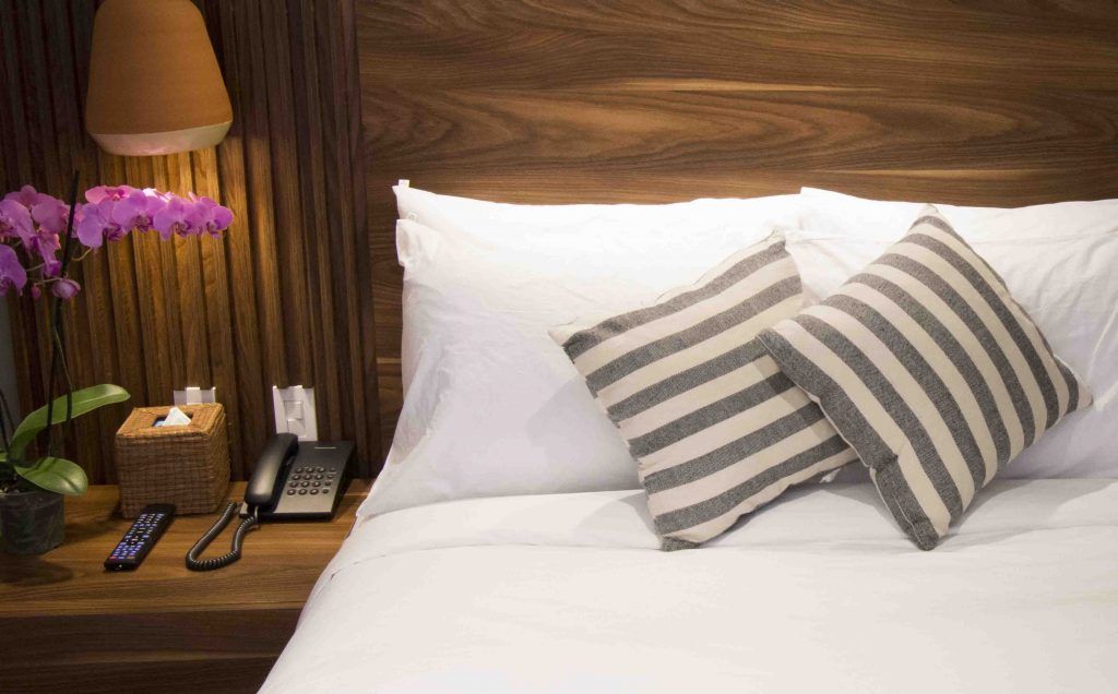 A bed with white sheets and striped pillows in a hotel room.
