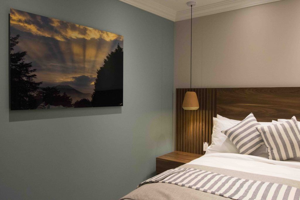 A bedroom with a large painting on the wall above the bed.