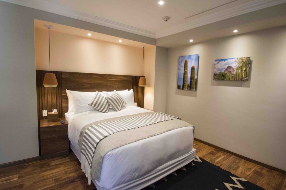 Una habitación de hotel con una cama tamaño king y dos mesitas de noche.