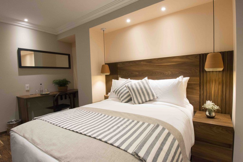 A hotel room with a large bed and a wooden headboard.