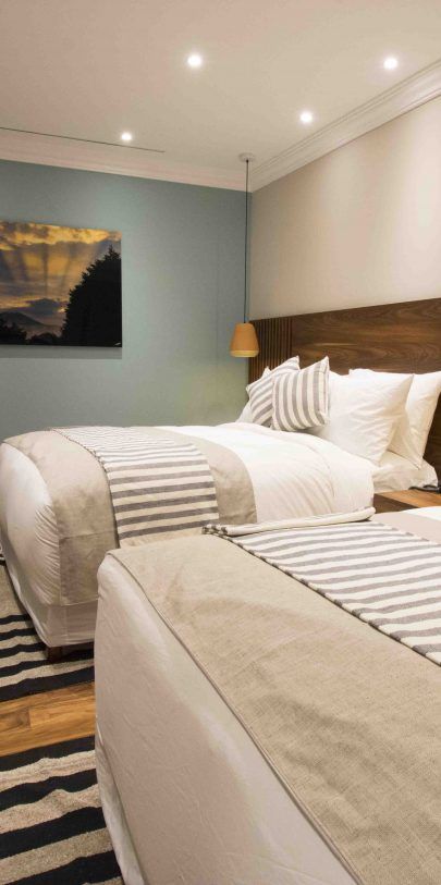 A hotel room with two beds and a striped rug.