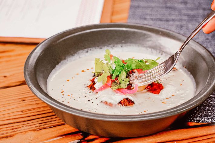 Una persona está comiendo un tazón de sopa con un tenedor.