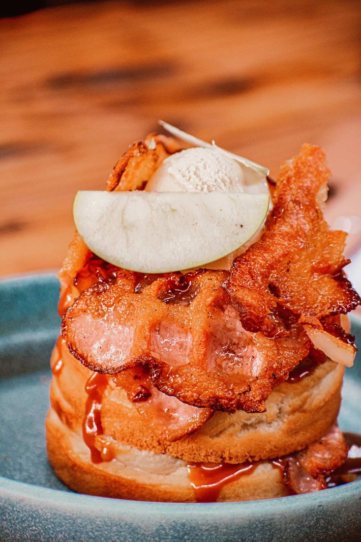 Un primer plano de un sándwich con tocino y manzanas en un plato.