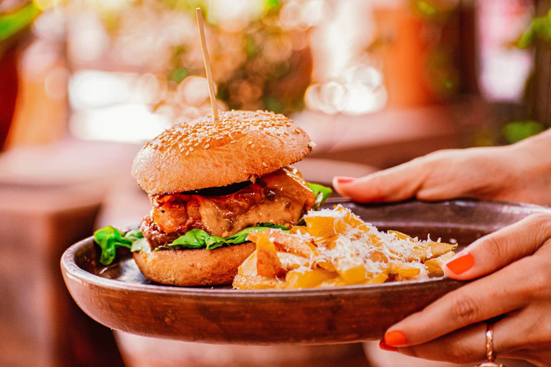 A person is holding a plate of food with a hamburger and french fries on it.