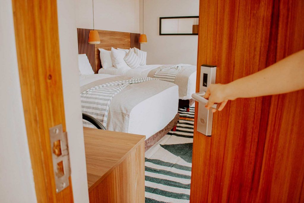 Una persona está abriendo una puerta de madera en una habitación de hotel.