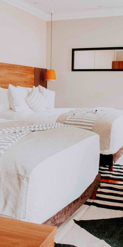 A hotel room with two beds and a rug.