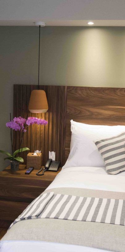 A hotel room with a bed , nightstand and lamp.