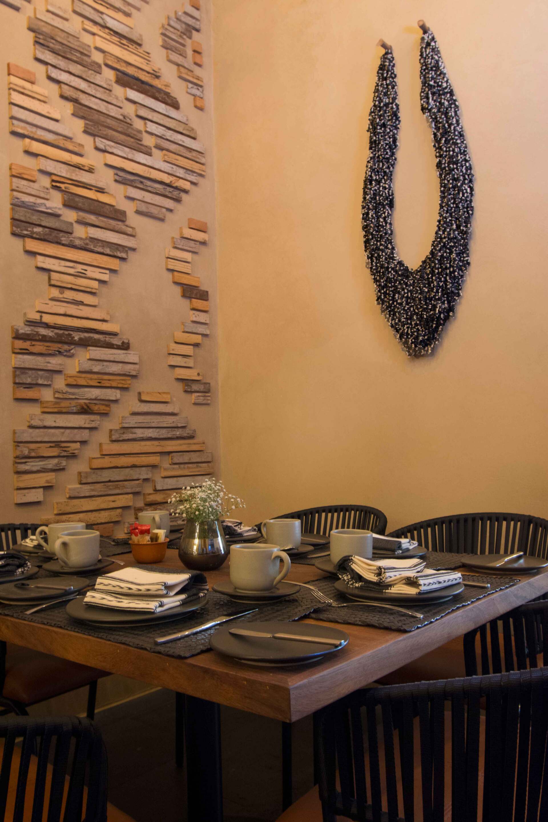 Un comedor con una mesa y sillas y una escultura en la pared.