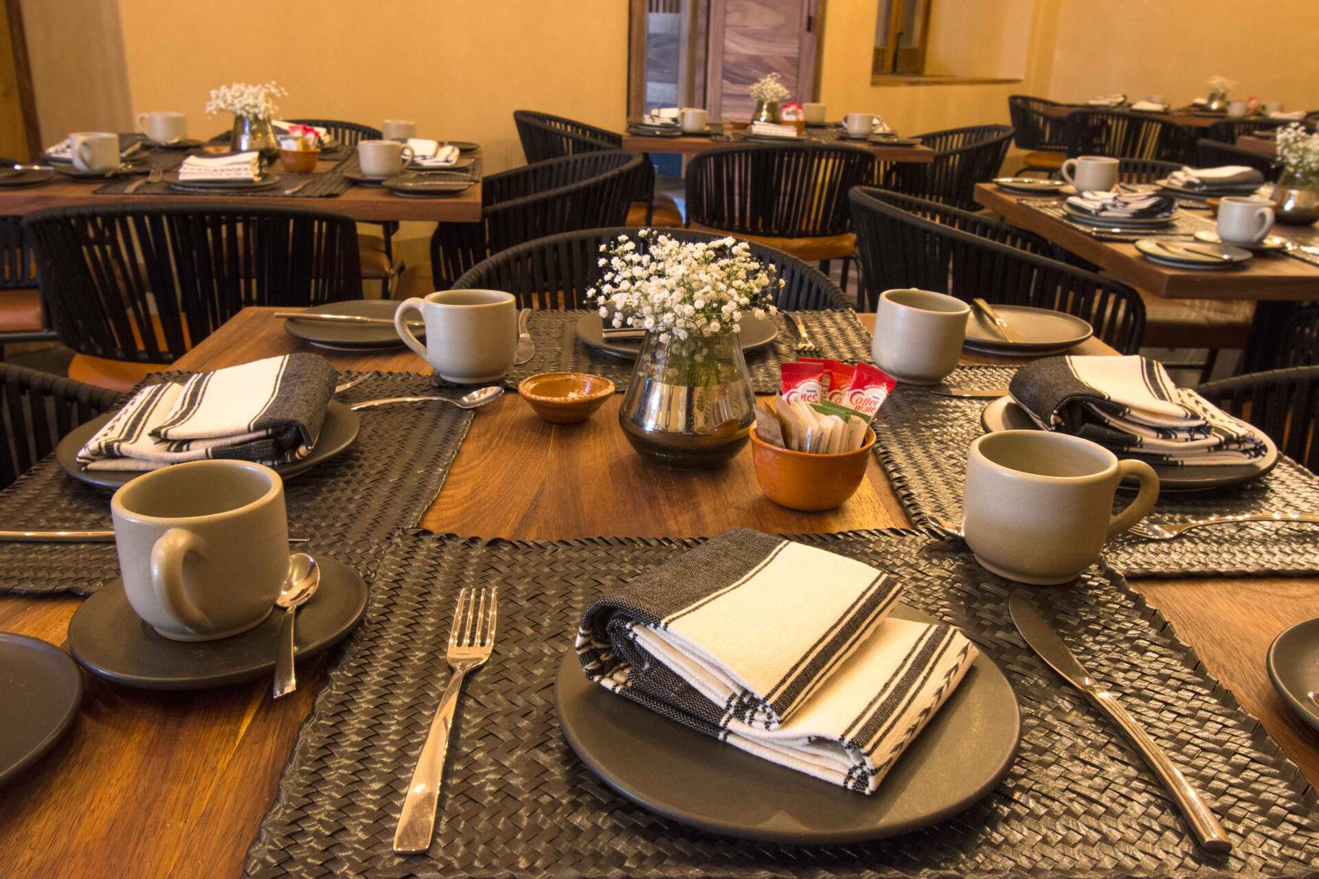 A dining room table with plates , cups , and silverware on it.