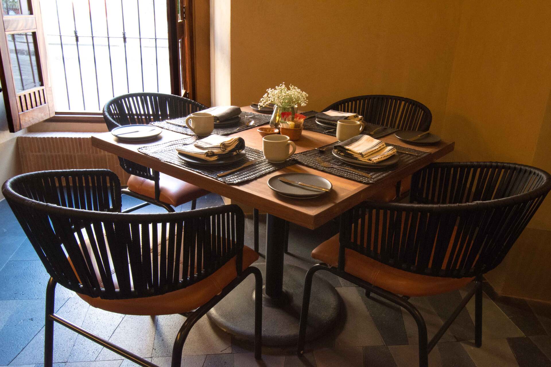 A dining room table with four chairs and plates on it