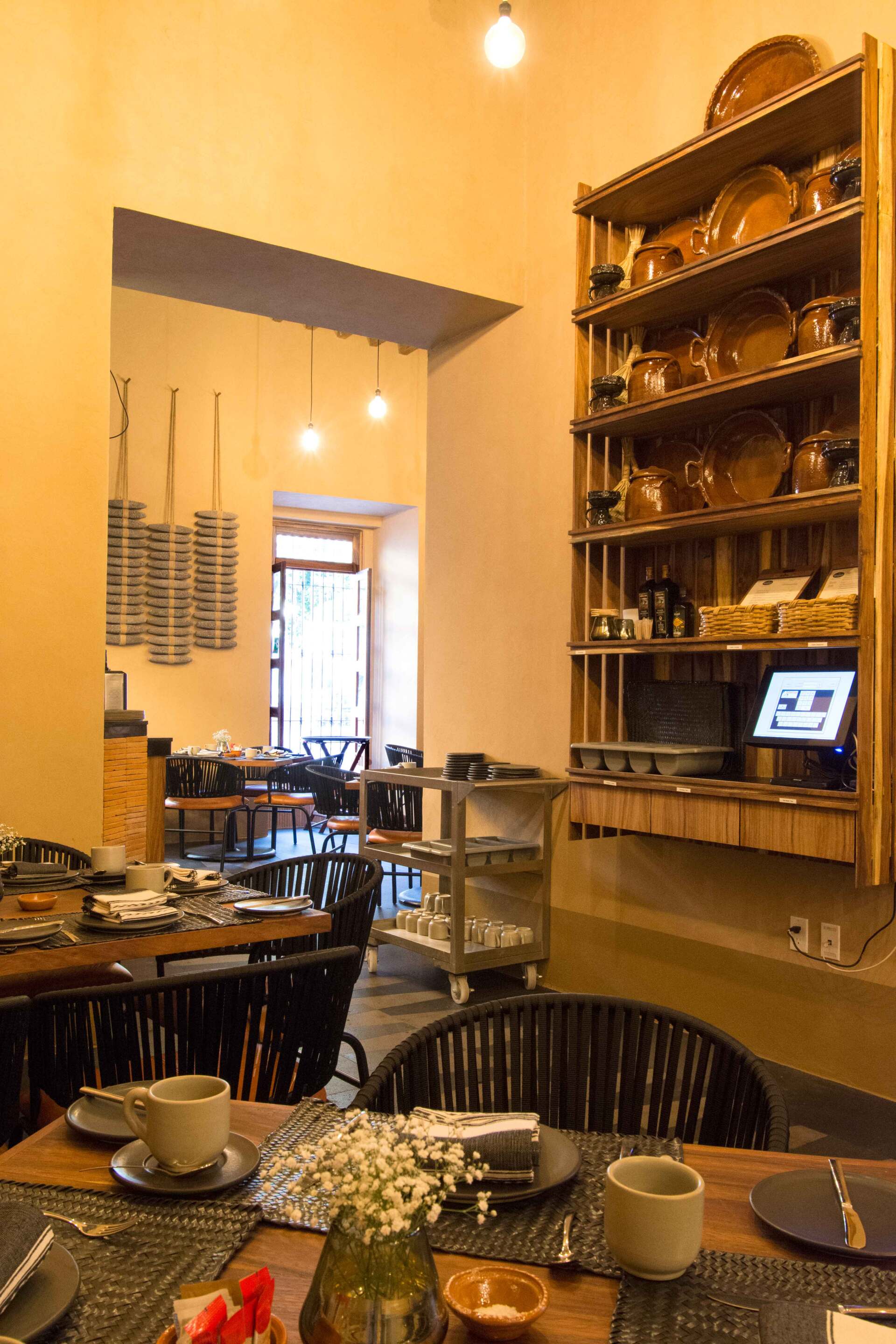 A restaurant with tables and chairs and a shelf with plates on it.