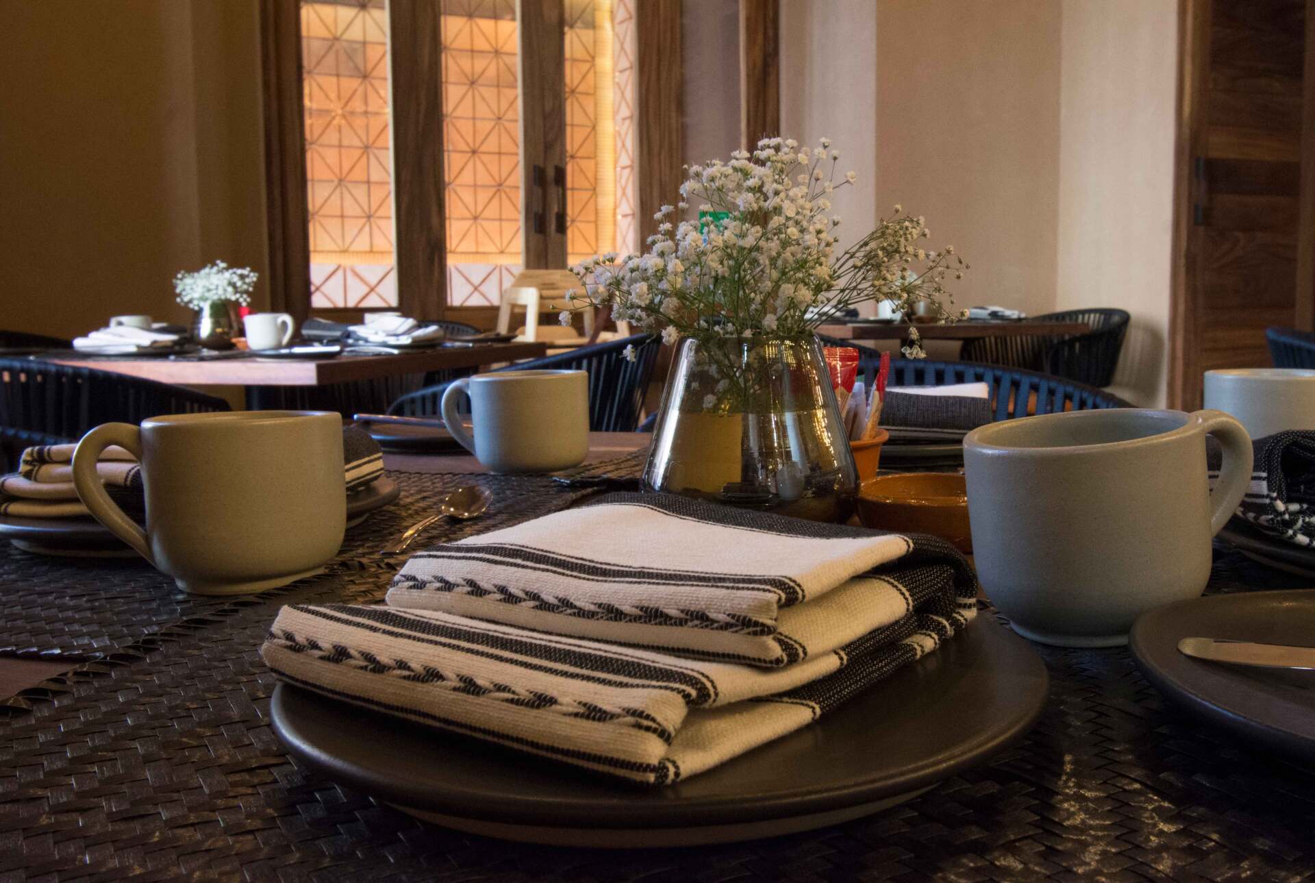 A table with plates , cups , napkins and a vase of flowers on it.