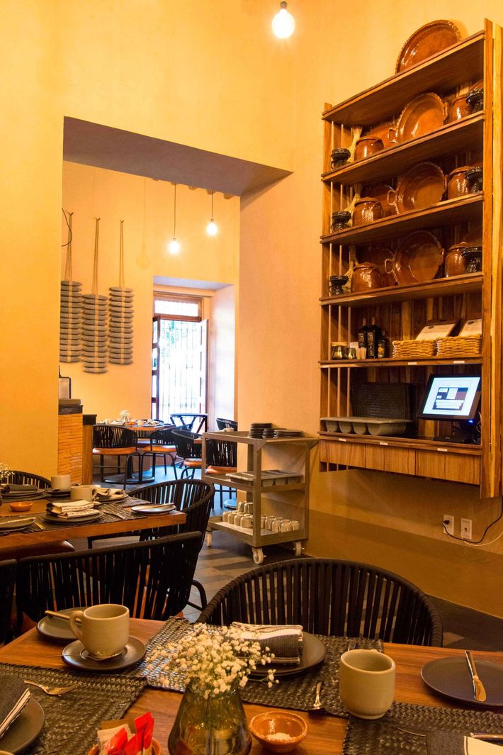 Un restaurante con mesas y sillas y un estante con platos encima.