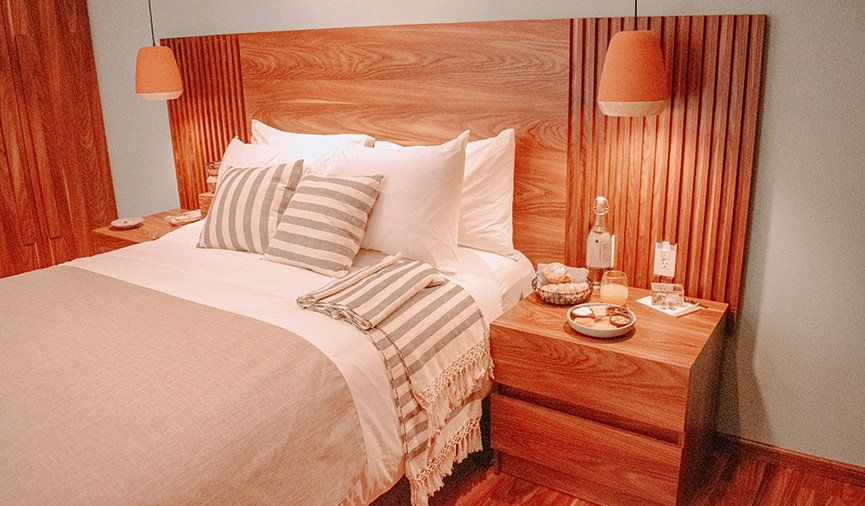 Un dormitorio con cama, mesita de noche y cabecero de madera.