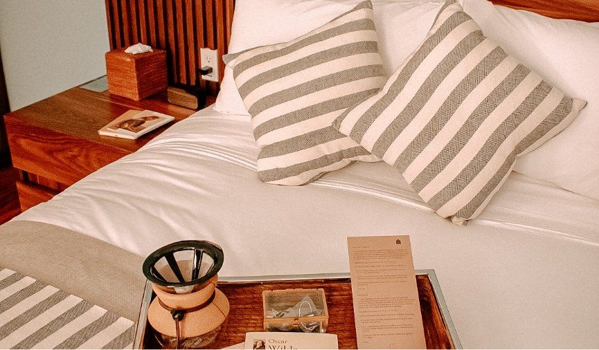 Una cama con almohadas a rayas y una bandeja encima.
