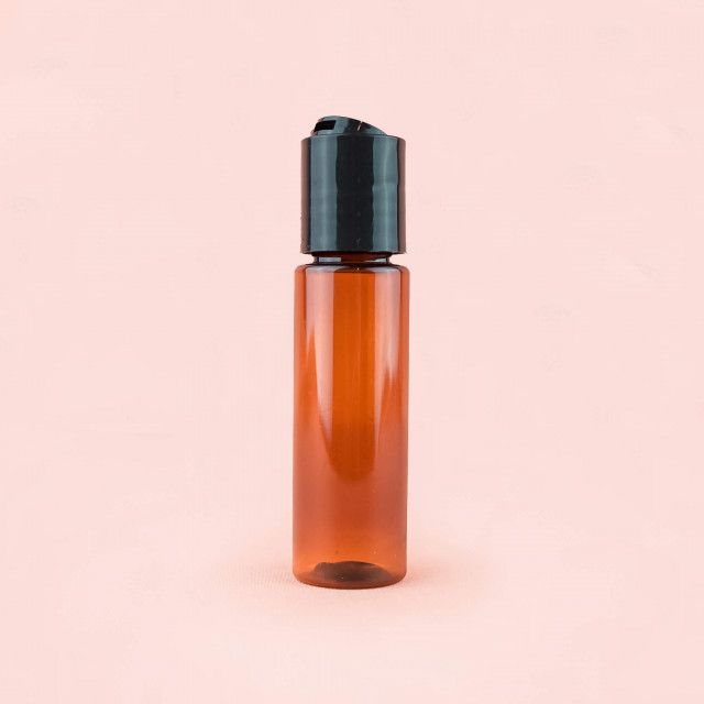 A brown plastic bottle with a black lid on a pink background.