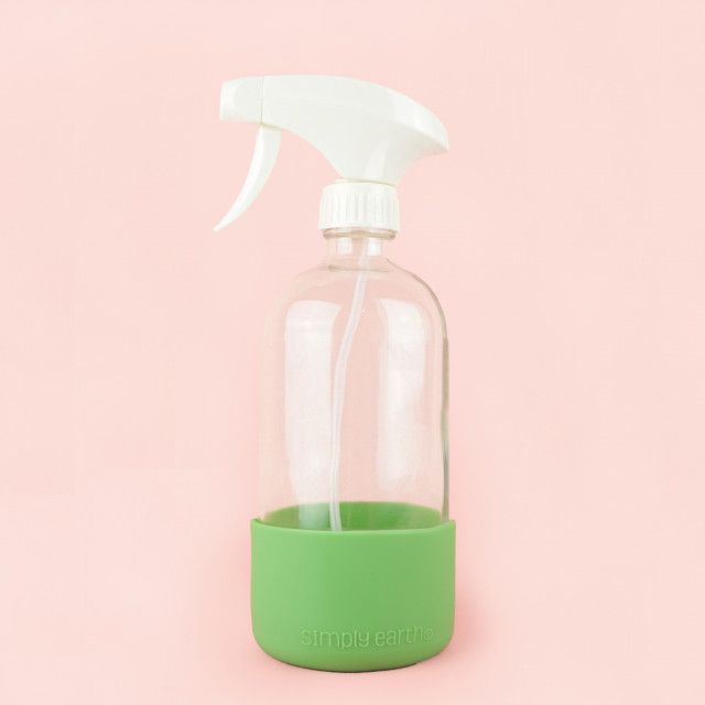 A spray bottle with a green silicone sleeve on a pink background.