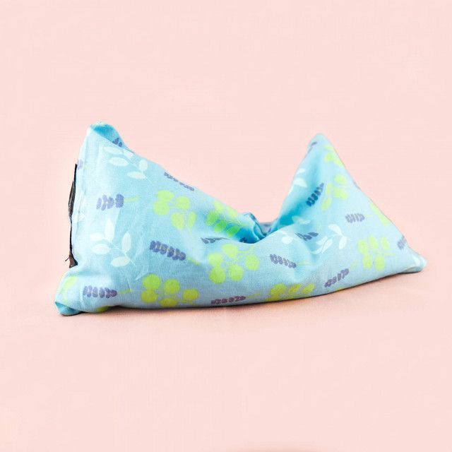 A blue pillow with a pattern on it is sitting on a pink surface.
