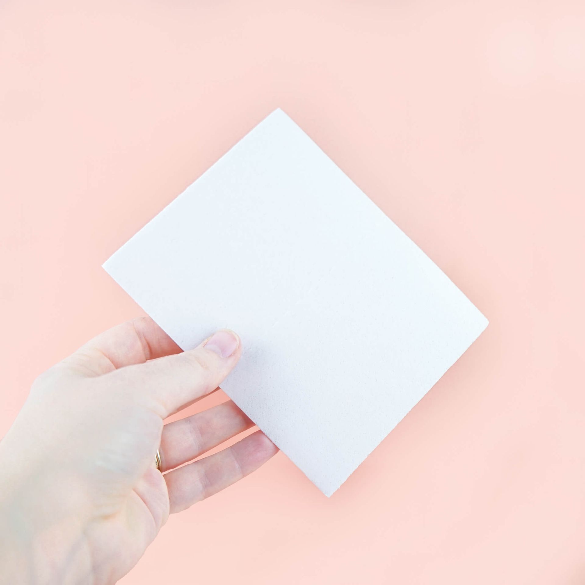 A box of laundry detergent sheets on a pink background.