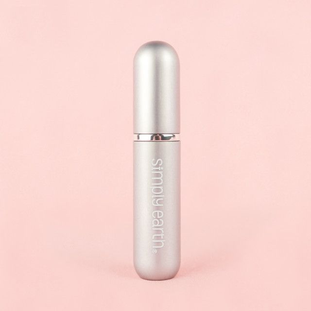 A bottle of simple faith perfume is sitting on a pink surface.