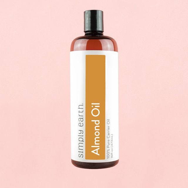 A bottle of simply earth almond oil on a pink background