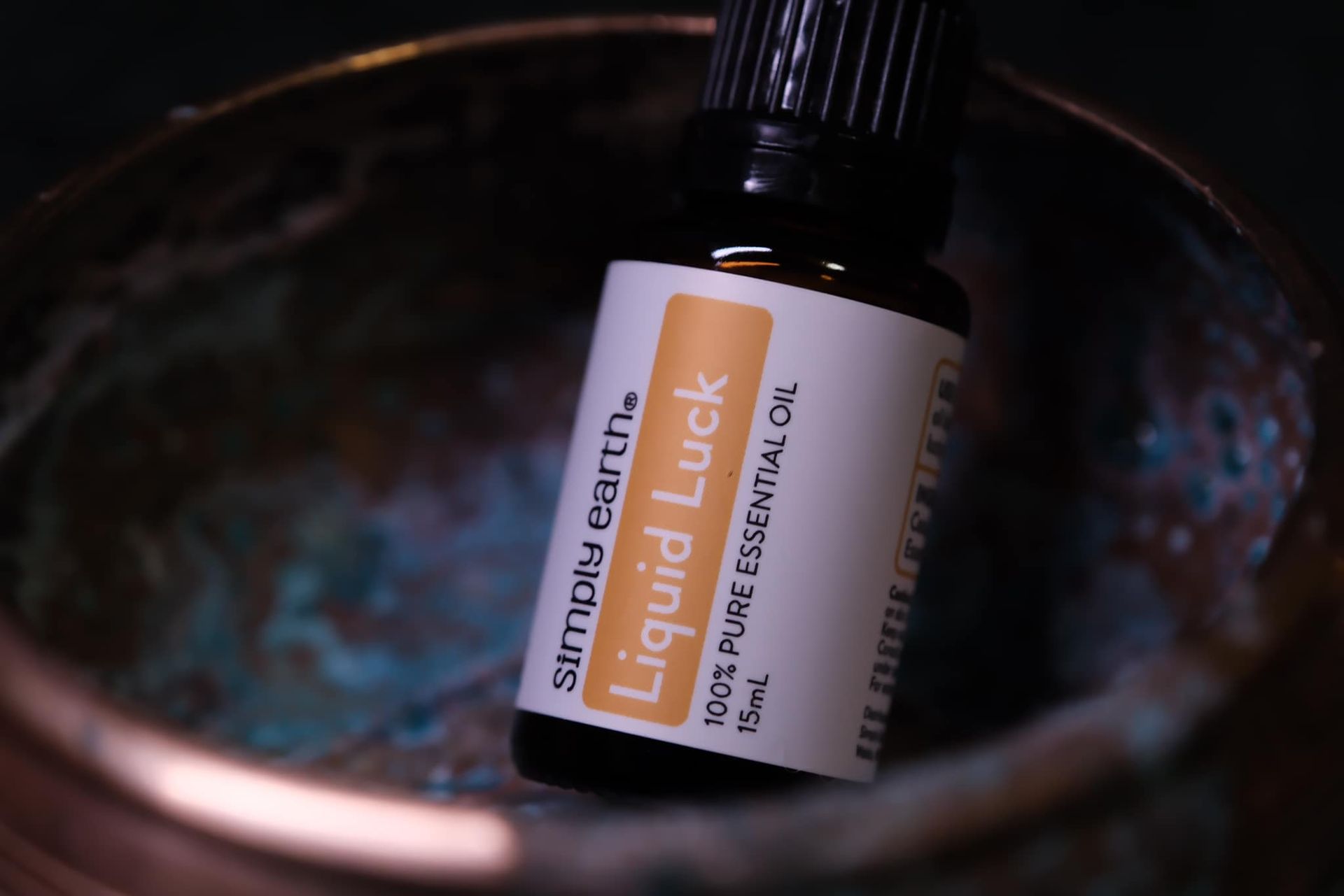 A bottle of liquid luck essential oil sits in a bowl