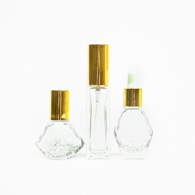 Three clear glass bottles with gold caps on a white background.
