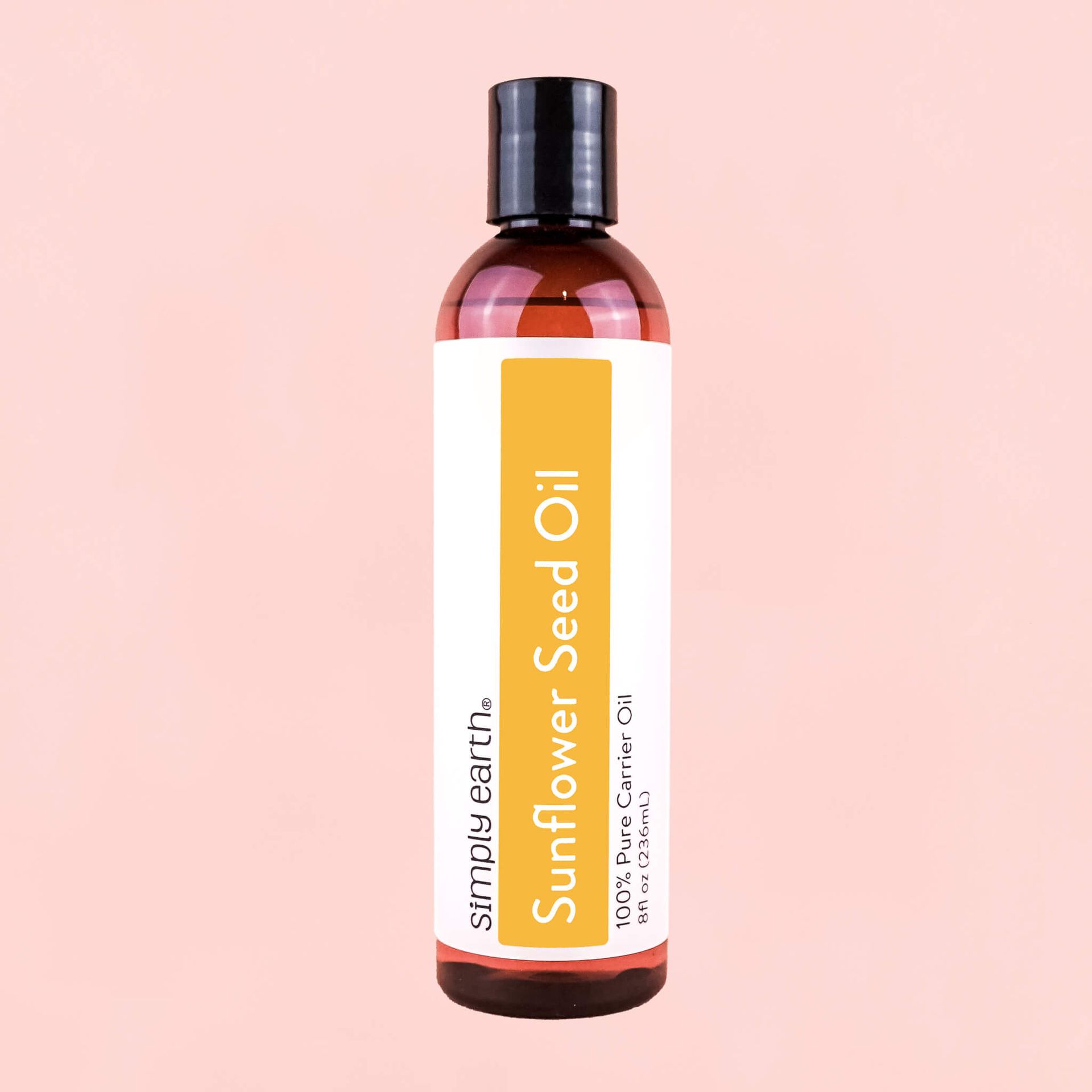 A bottle of sunflower seed oil on a pink background