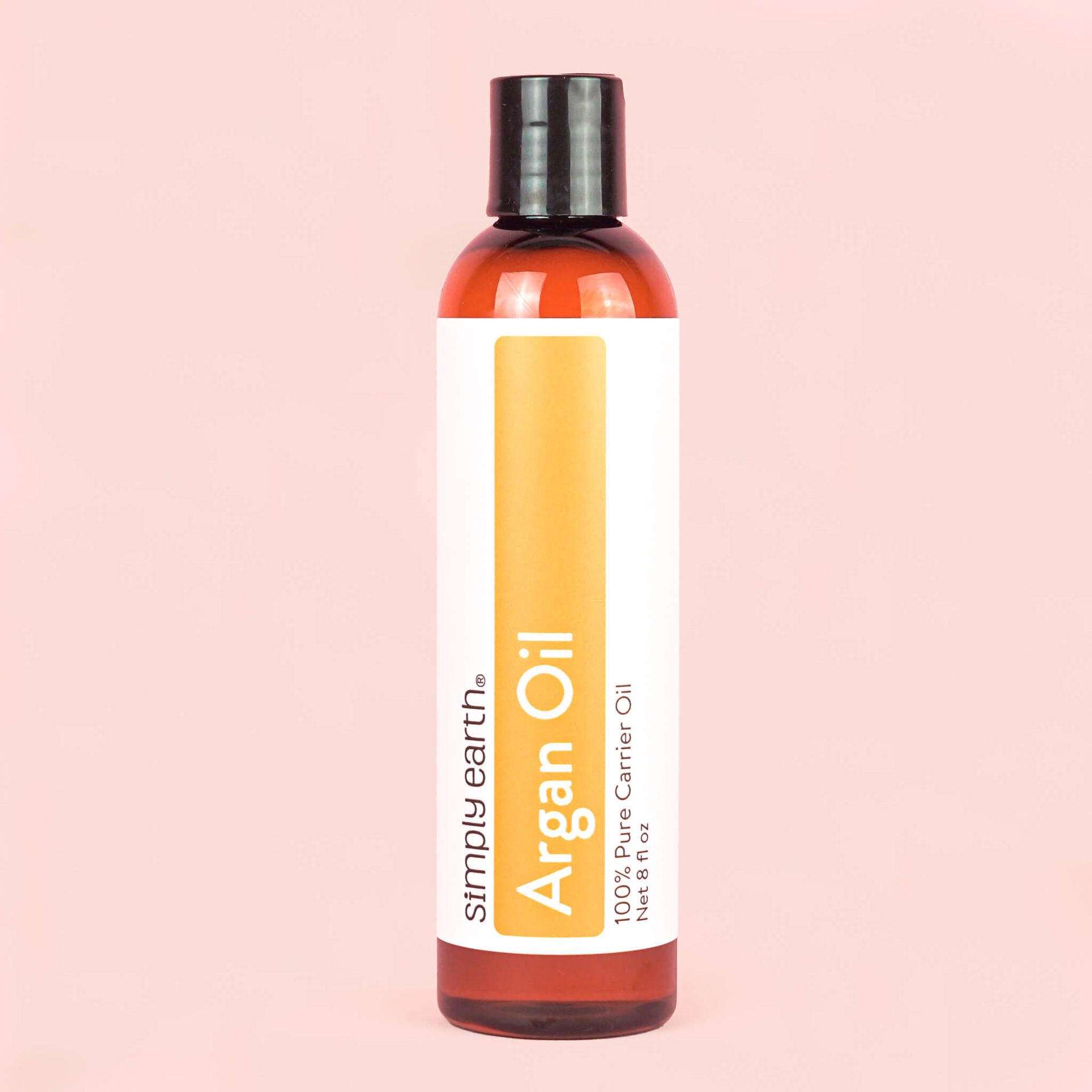 A bottle of argan oil on a pink background