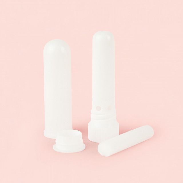 Three white nasal inhalers are sitting on a pink surface.