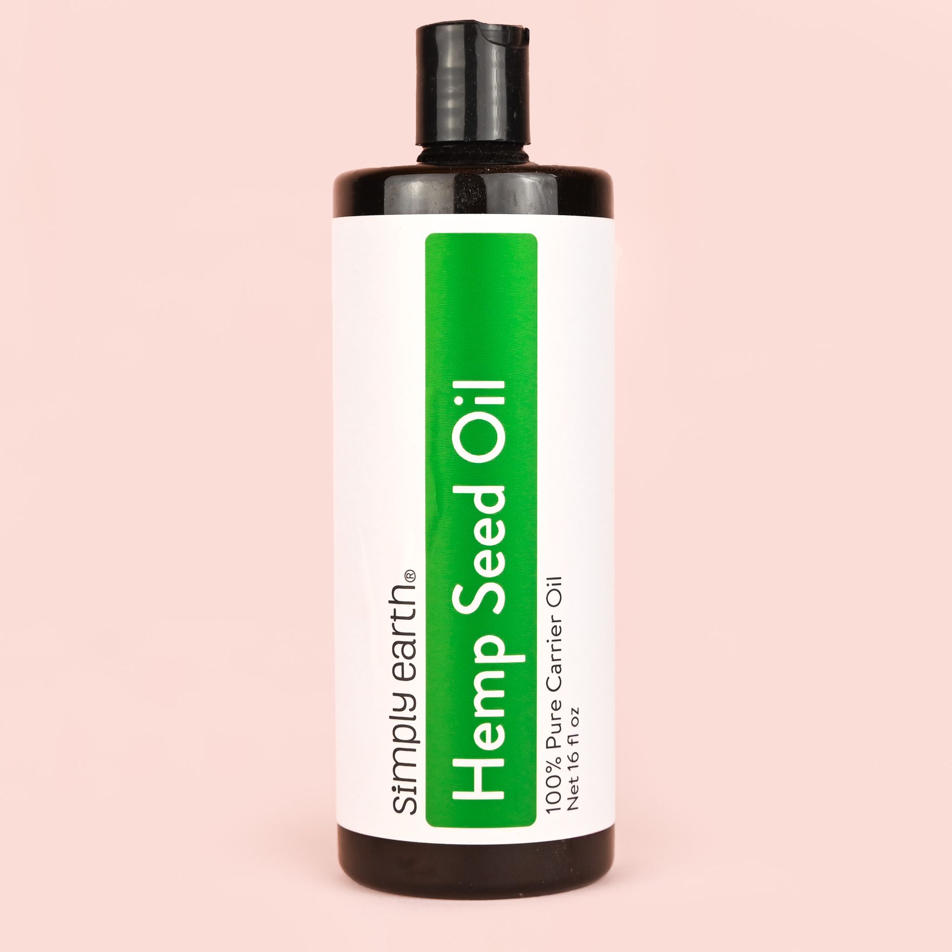 A bottle of hemp seed oil is sitting on a pink surface.