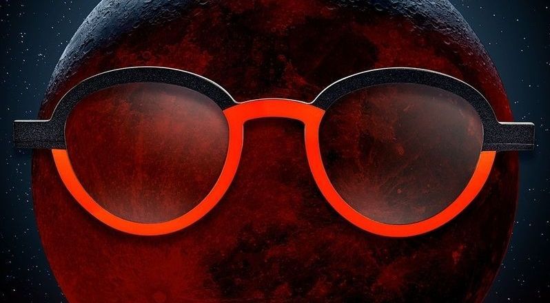 Un paio di occhiali è seduto davanti a un pianeta rosso.