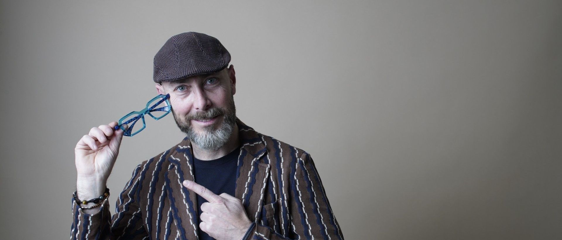 Un uomo che indossa un cappello e occhiali indica i suoi occhiali.