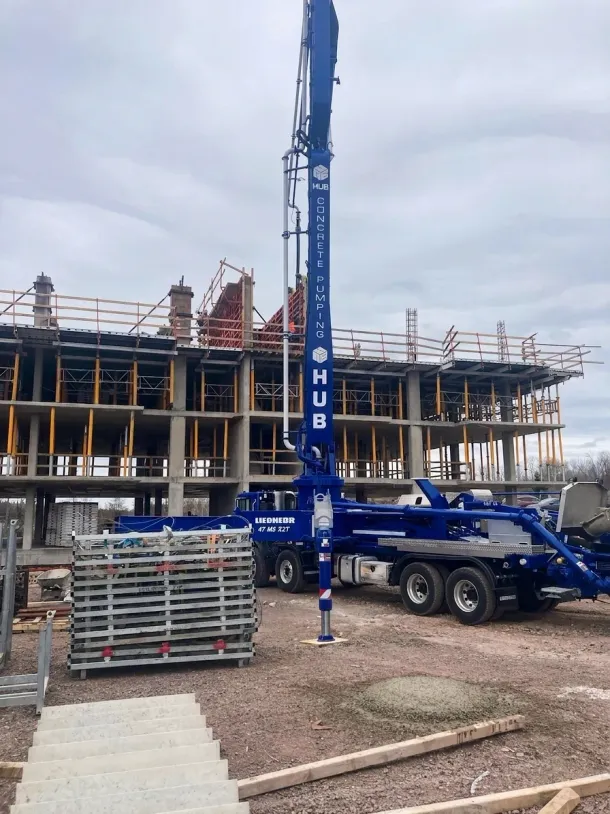 Blue mobile crane at a construction site beside a partially built concrete structure.