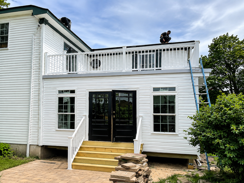 White house exterior with upstairs balcony, double doors, and front steps