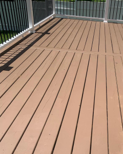 Brown wooden deck with black railings and a view of water or lawn beyond