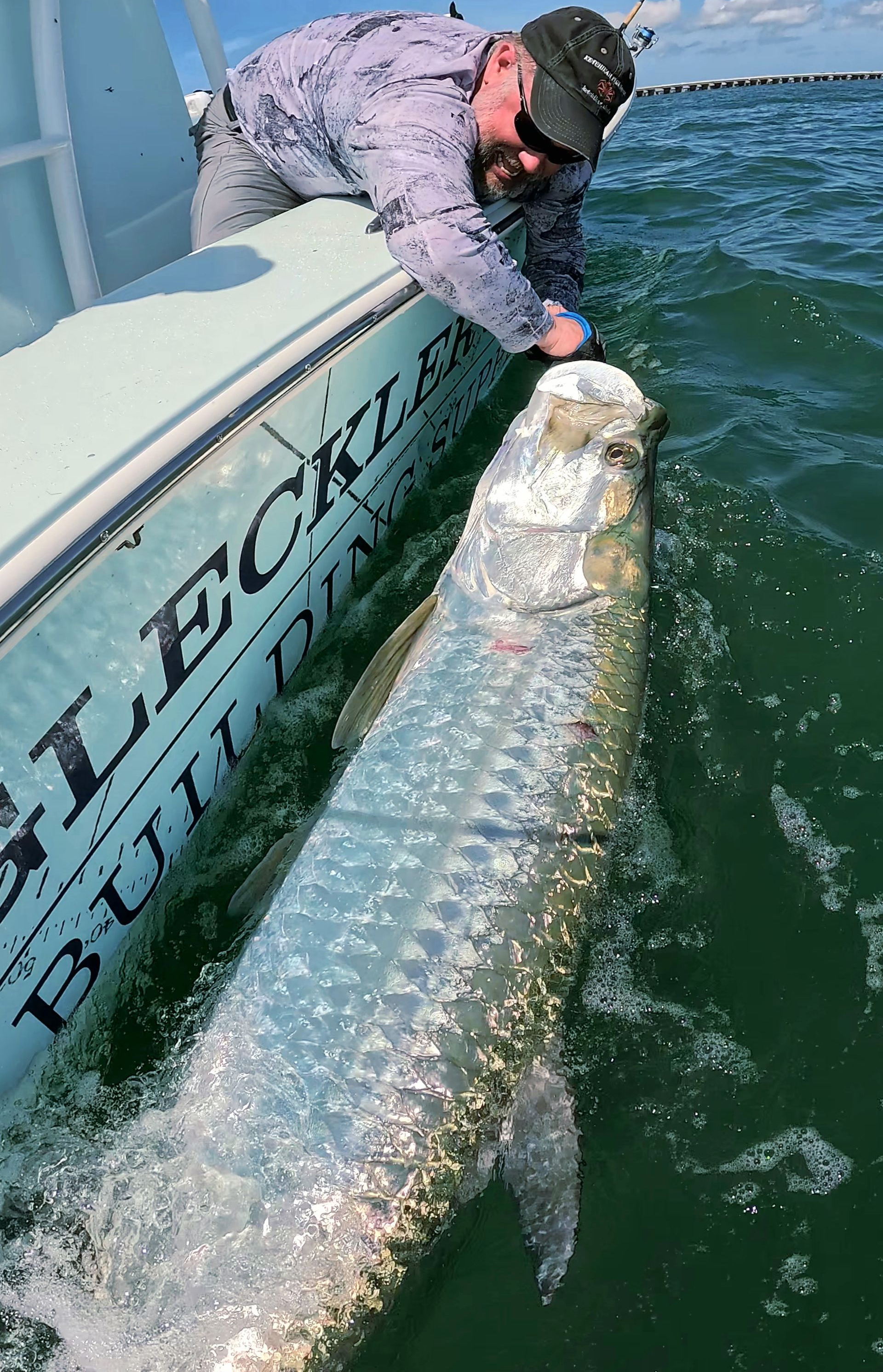 A man is holding a large fish in the water.