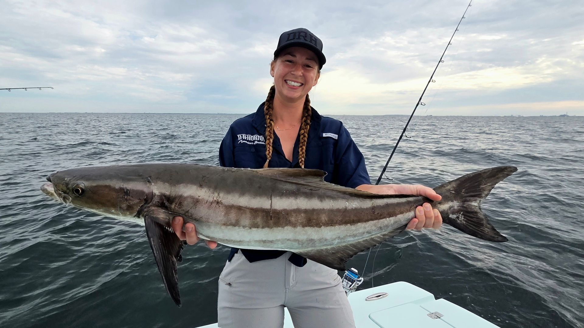 A woman is holding a large fish on a boat.