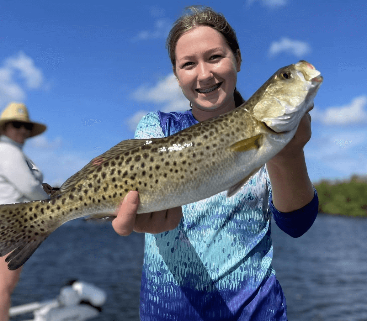 A woman is holding a large fish in her hands