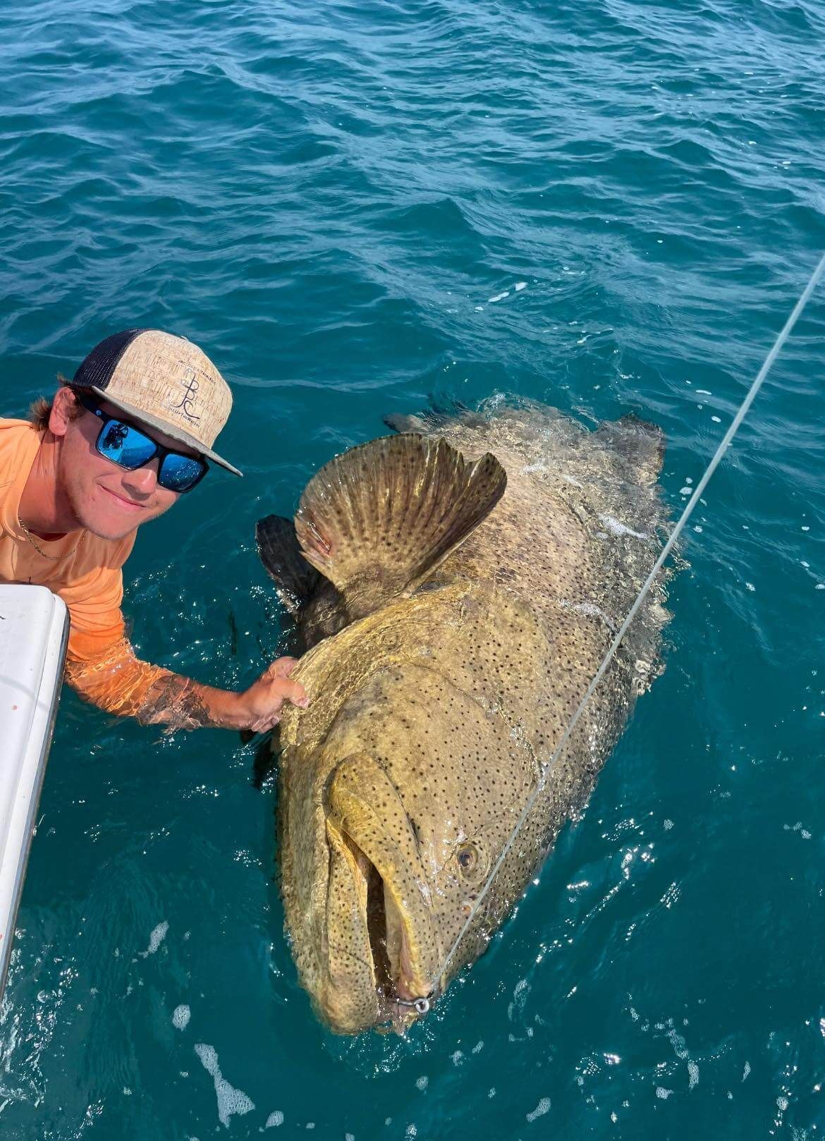 A man is holding a large fish in the water.