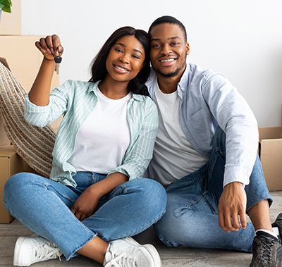 Smiling couple sitting on the floor, holding hands in a bright living room