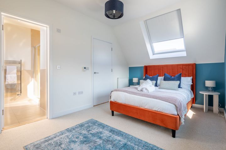 A bedroom with a large bed and a blue rug.
